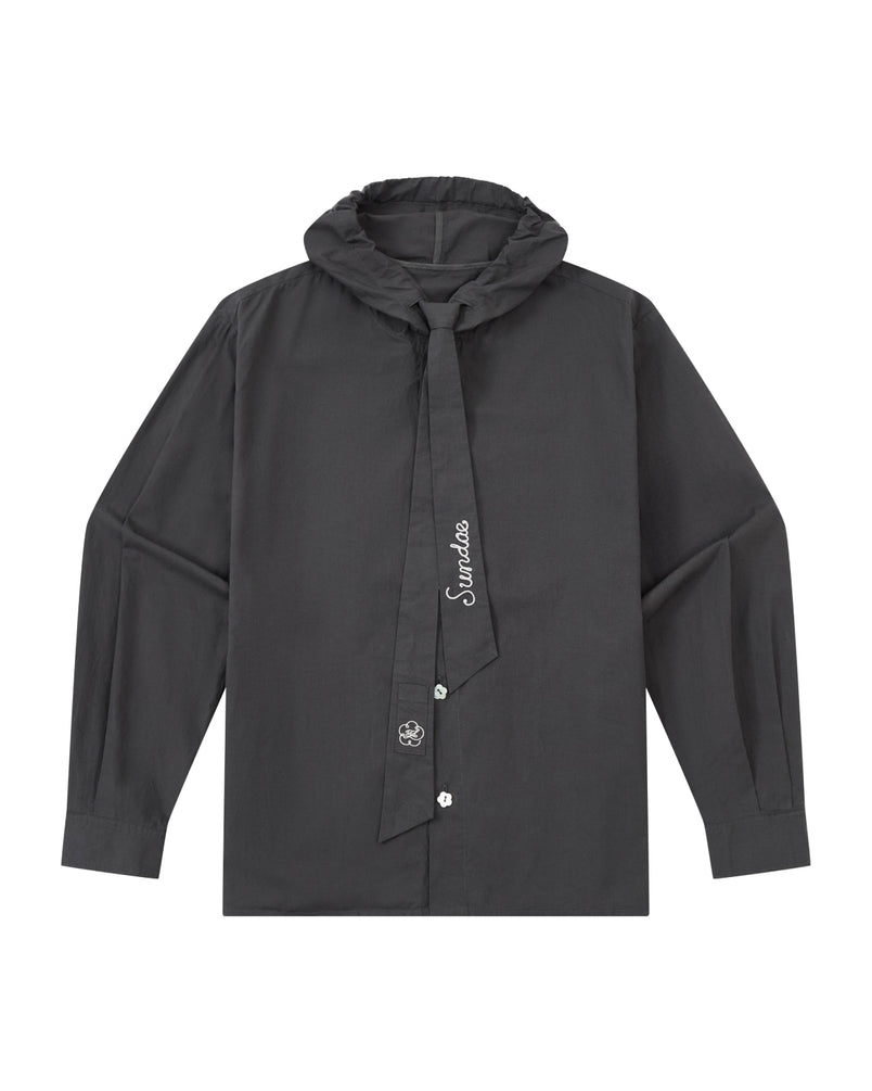 The CHARCOAL SUNBAE TIE SHIRT by Sundae School is a long-sleeve black button-up with a ruffled collar and an attached necktie adorned with white embroidery, featuring a simple, modern design.
