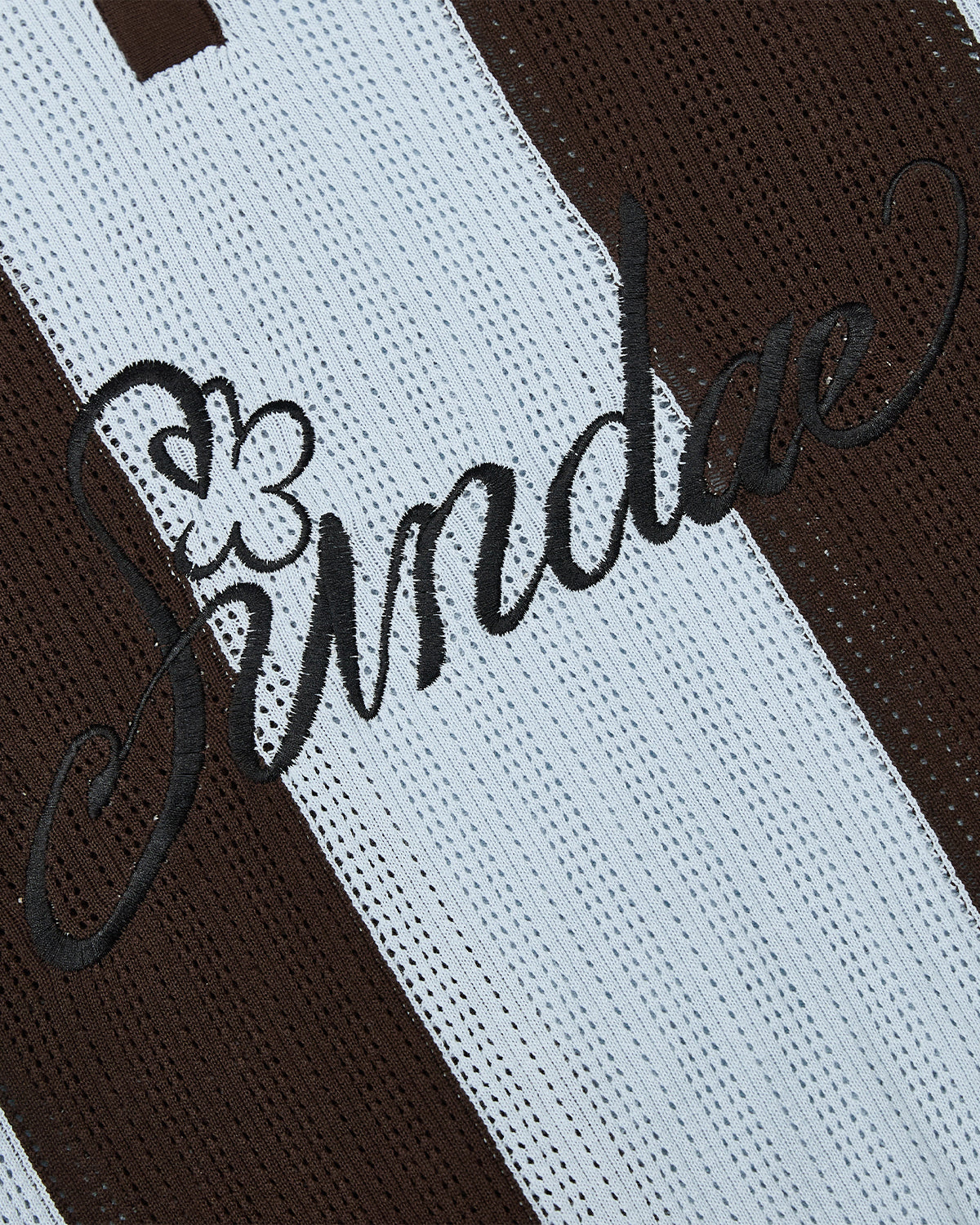 Close-up of the SKY BLUE SUNDAE SOCCER JERSEY by Sundae School, a cotton lightweight top with alternating brown and white vertical stripes, featuring the word “Sundae” embroidered in black cursive lettering with a small flower accent on the S.