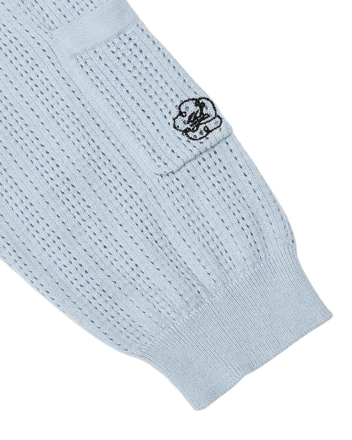 The SKY BLUE SUNDAE SOCCER JERSEY by Sundae School features a light blue knitted sleeve with a ribbed texture and a small rectangular pocket. Near the top of the pocket, an embroidered black design resembling a cloud and face adds to the playful charm of this lightweight cotton top.