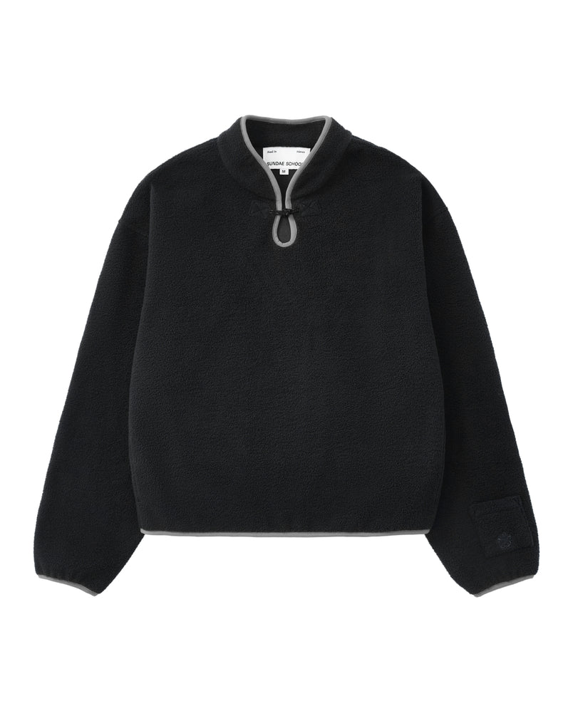 The BLACK TEARDROP KNOT FLEECE by Sundae School is a black, cozy fleece pullover featuring a high collar with grey trim and a distinctive small loop detail at the neck. This relaxed-fit garment has long sleeves and is finished with subtle East Asian-inspired fleece accents for a unique touch.