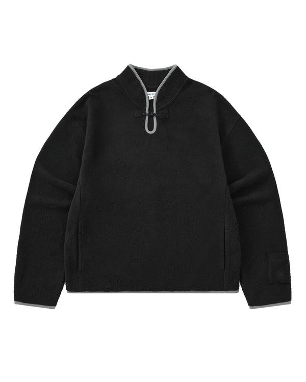 BLACK TEARDROP KNOT FLEECE by Sundae School: A black cozy fleece pullover featuring a high collar, gray trim accents, a distinctive front teardrop loop detail, side pockets, and a branded patch on the left sleeve. The garment is displayed laid flat against a white background.