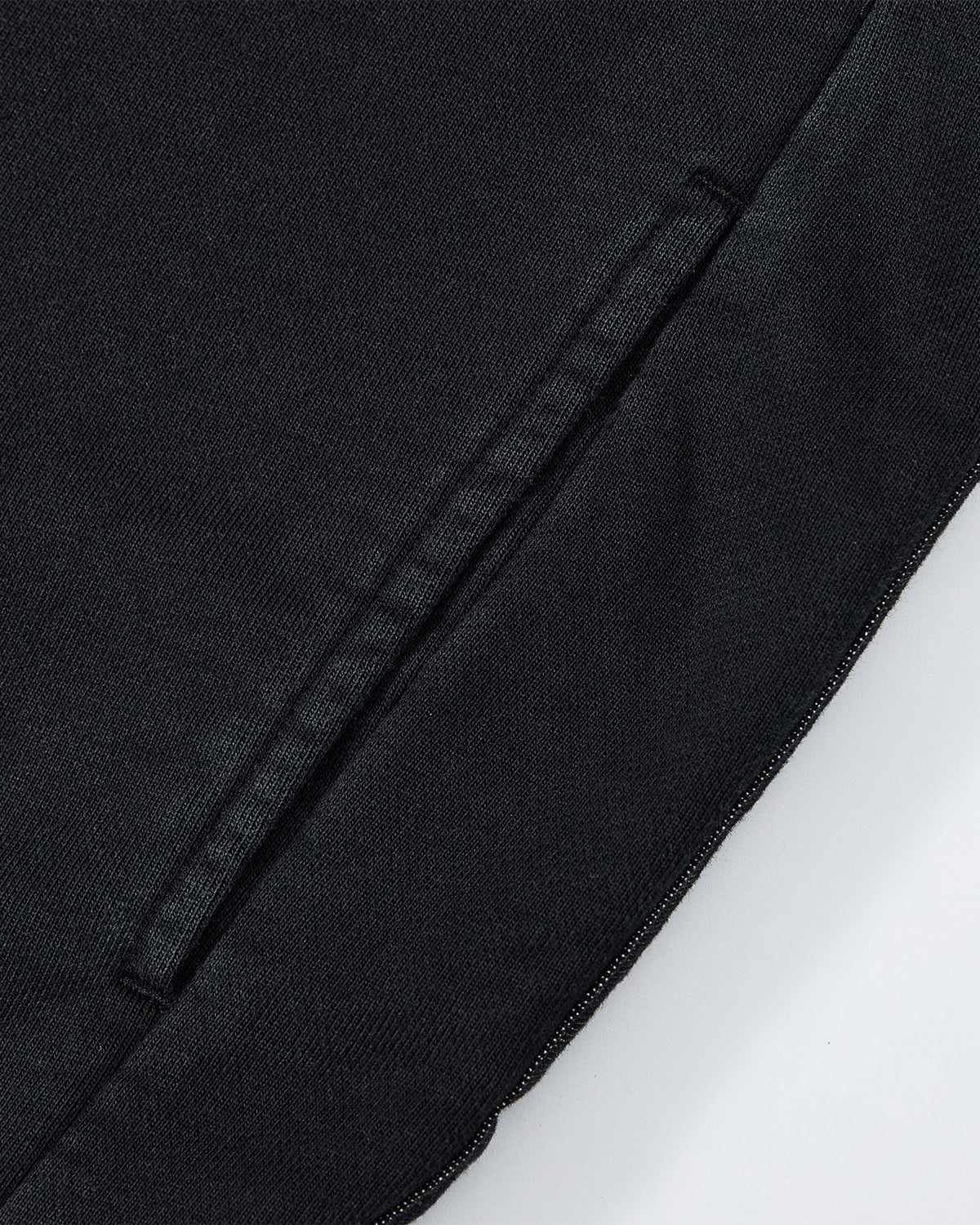 Close-up of the BLACK TEARDROP KNOT SWEATSHIRT by Sundae School, featuring a neatly stitched diagonal slit pocket and clean seams on black cotton fabric with visible texture.