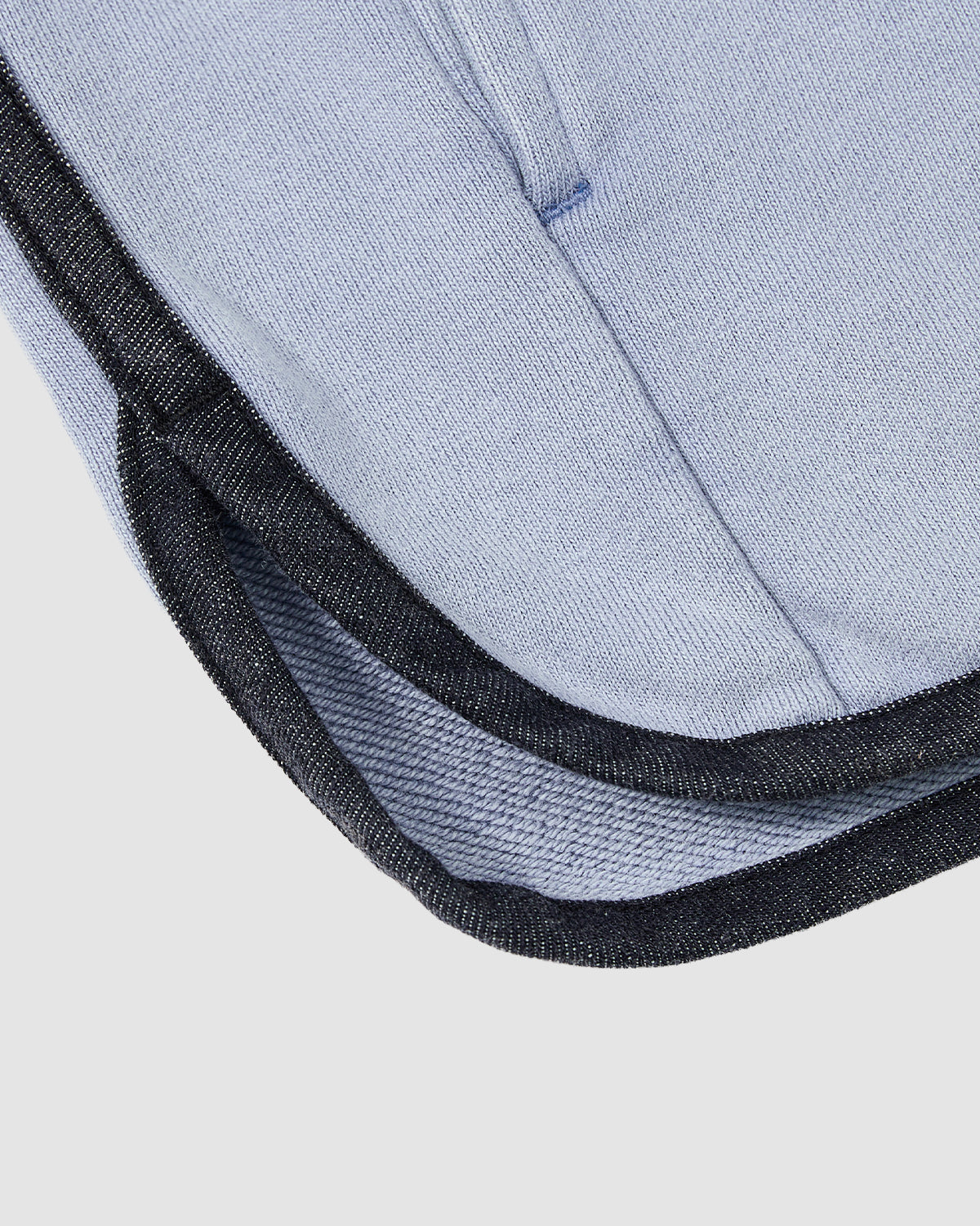 Close-up of Sundae School’s SKY BLUE TEARDROP KNOT SWEATSHIRT, featuring light blue 100% cotton fabric and black denim trim, shown against a plain light gray background.