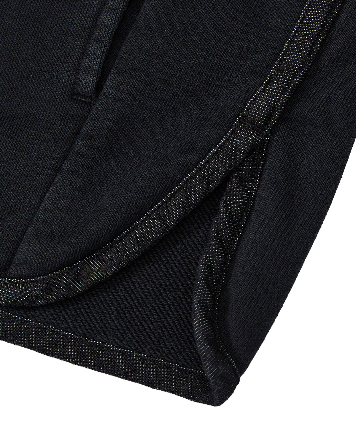 Close-up of the hem and side seam of the BLACK TEARDROP KNOT SWEATSHIRT by Sundae School, highlighting the intricate stitching and fabric texture with a curved edge—demonstrating craftsmanship akin to that found in a vintage denim-trim sweater or a 100% cotton sweatshirt.