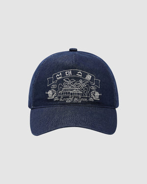 The INDIGO DENIM TIGER CAP by Sundae School is a navy blue adjustable six-panel cap featuring Korean folk-art embroidery of a building, trees, banners, and stylized details above and below the central graphic.