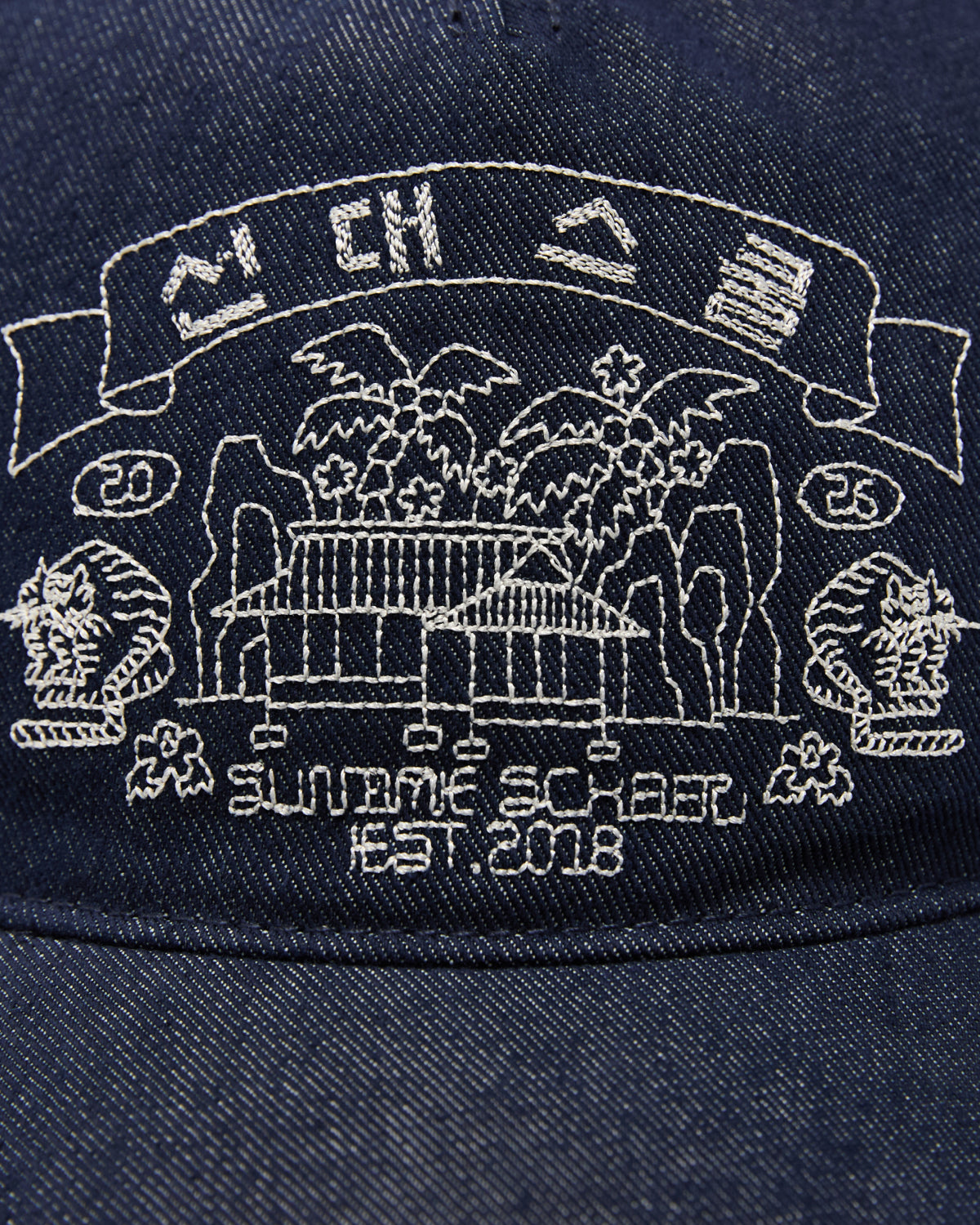 Close-up of the Sundae School INDIGO DENIM TIGER CAP, an adjustable six-panel strapback hat featuring Korean folk-art embroidery with a traditional building, trees, mountains, SUNDAE SCHOOL EST. 2018 text, 2025, and symbols above the scene.