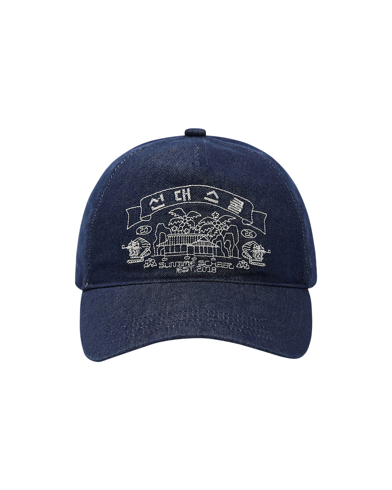 Introducing the TIGER DEN CAP by Sundae School—a navy blue baseball cap crafted from a premium cotton blend for exceptional comfort. This denim strapback hat features intricate white embroidery on the front, depicting buildings, trees, and a banner with stylized text inspired by traditional Korean folk-art. Add a unique cultural accent to any outfit with this standout piece.