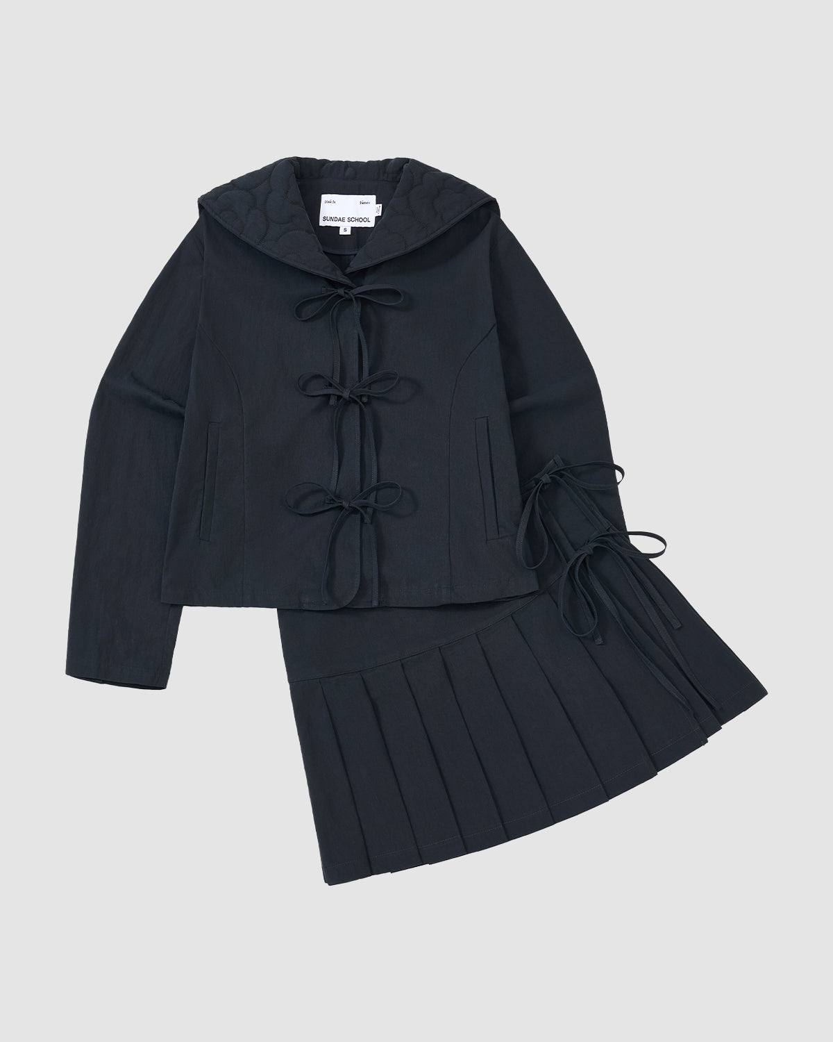 The Sundae School NAVY SAILOR COLLAR UNIFORM JACKET, a dark navy two-piece set with bow ties and a pleated skirt, is displayed flat on a light gray background.