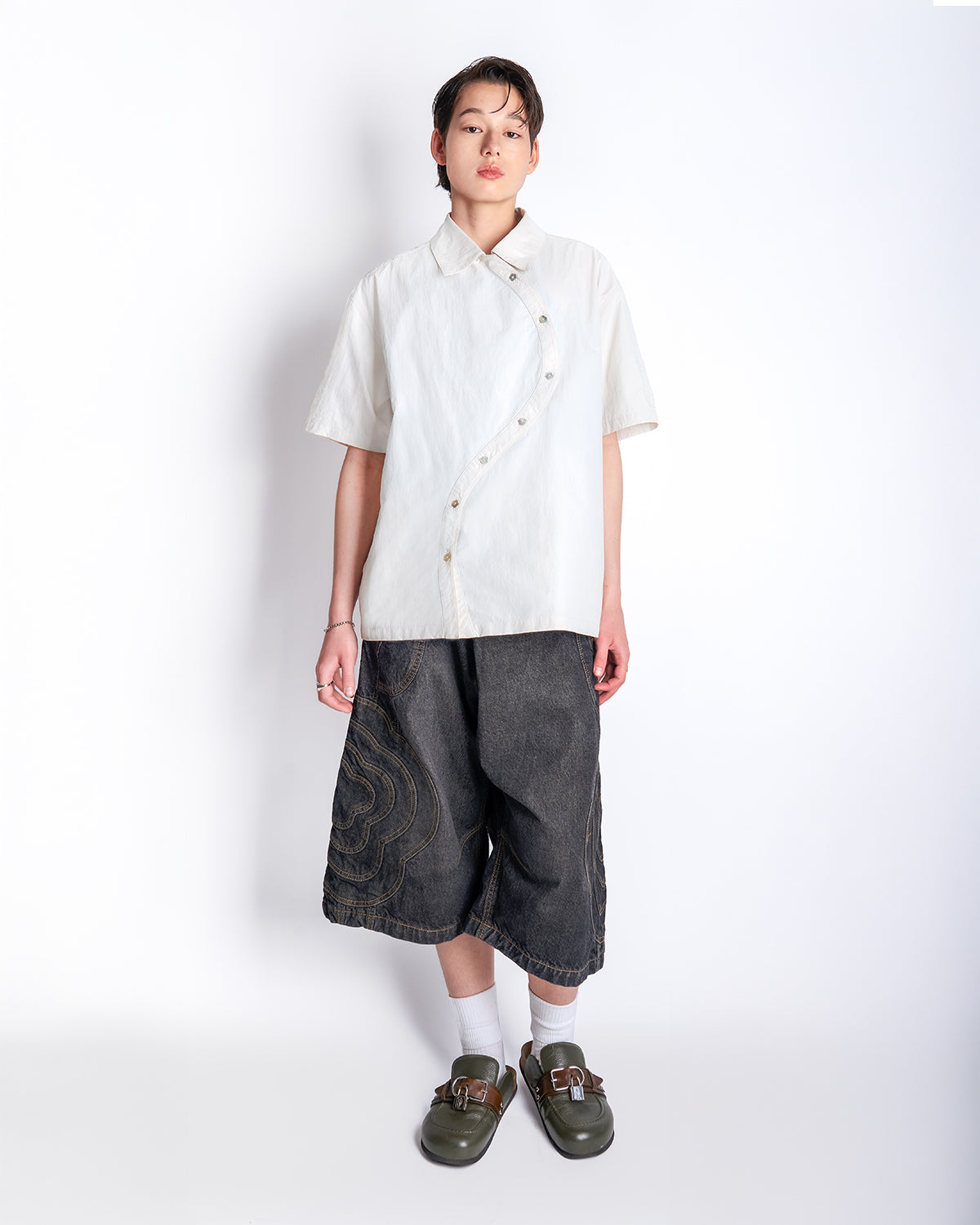 Model wearing the off-white Ivory Yin Yang Short Sleeve Shirt styled with gray patterned shorts, white socks, and brown leather loafers.