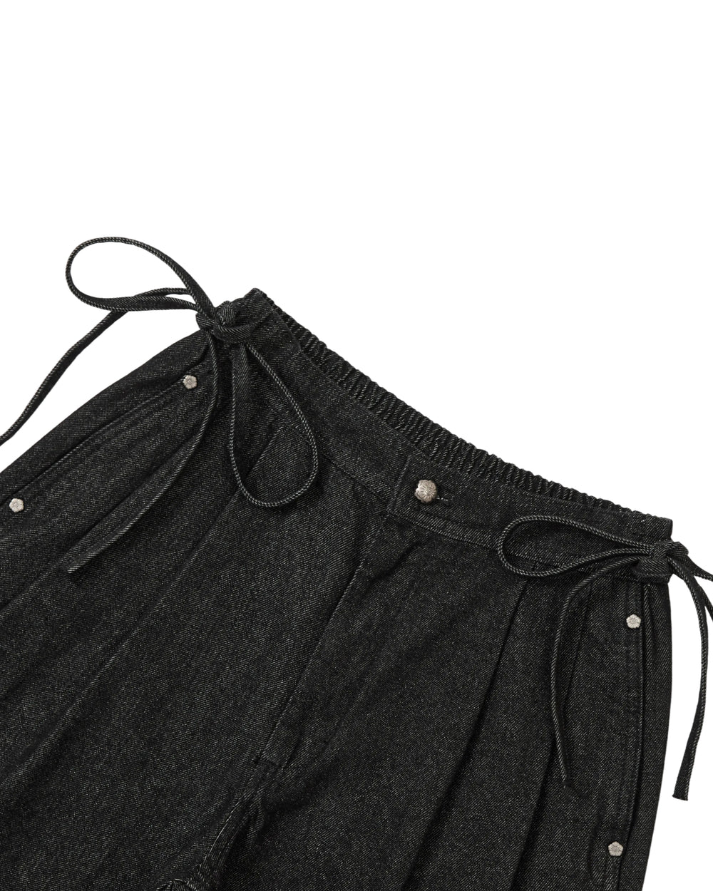 Close-up of Sundae School’s BLACK VITA JORTS, featuring an elastic waistband with silver snap buttons and hip ties, wide-leg silhouette, and laid flat against a white background.
