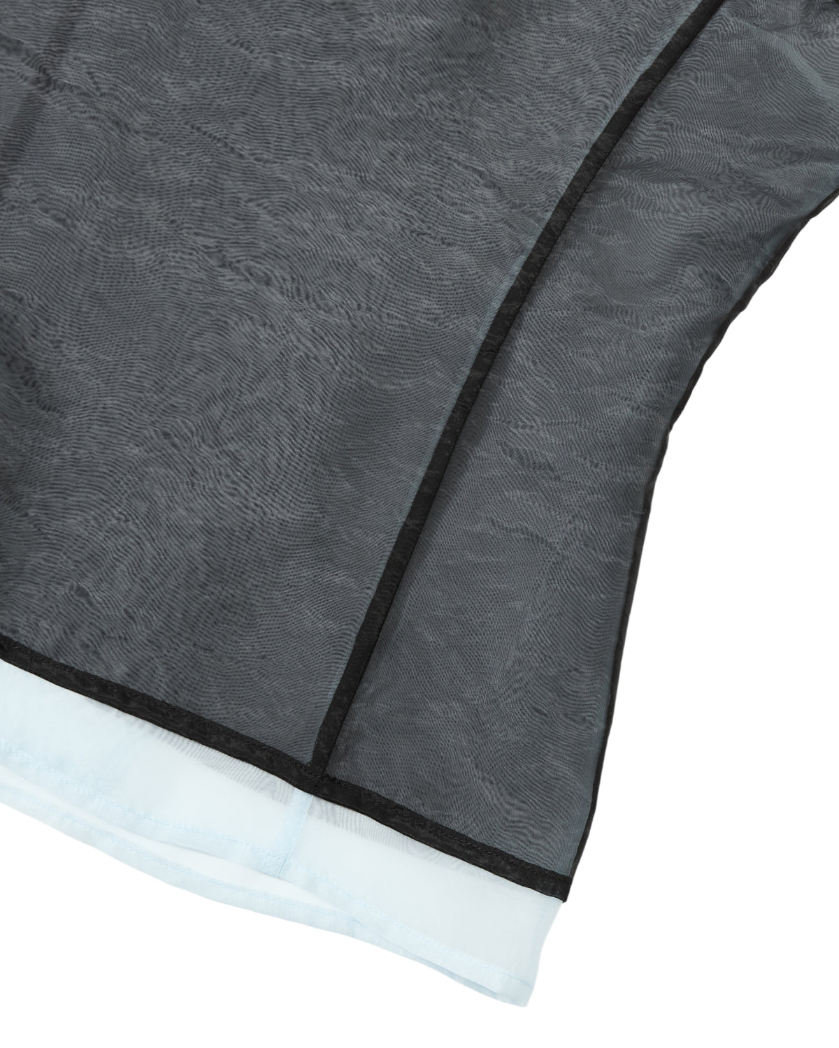 Close-up of the VITA ORGANZA VEST by Sundae School, showcasing sheer black double-layered organza with visible seams over a light blue underlayer, forming part of the garment.