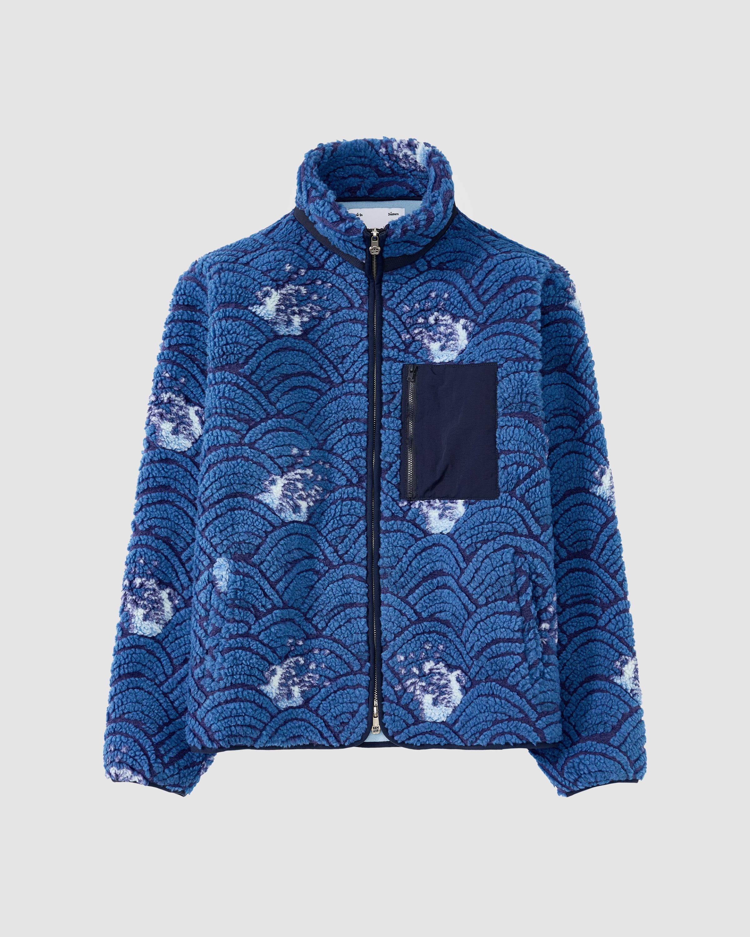 The BLUE WAVE FLEECE by Sundae School is a blue embossed pile fleece jacket with a black zip front, custom wave jacquard inspired by Korean ocean patterns, white accents, a navy chest pocket, and a high collar.