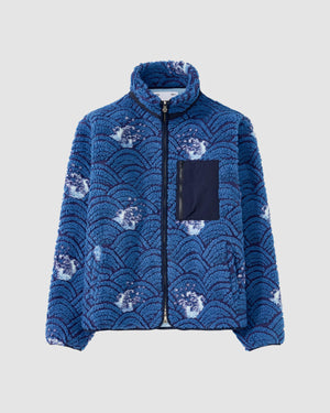 The BLUE WAVE FLEECE by Sundae School is a blue embossed pile fleece jacket with a black zip front, custom wave jacquard inspired by Korean ocean patterns, white accents, a navy chest pocket, and a high collar.