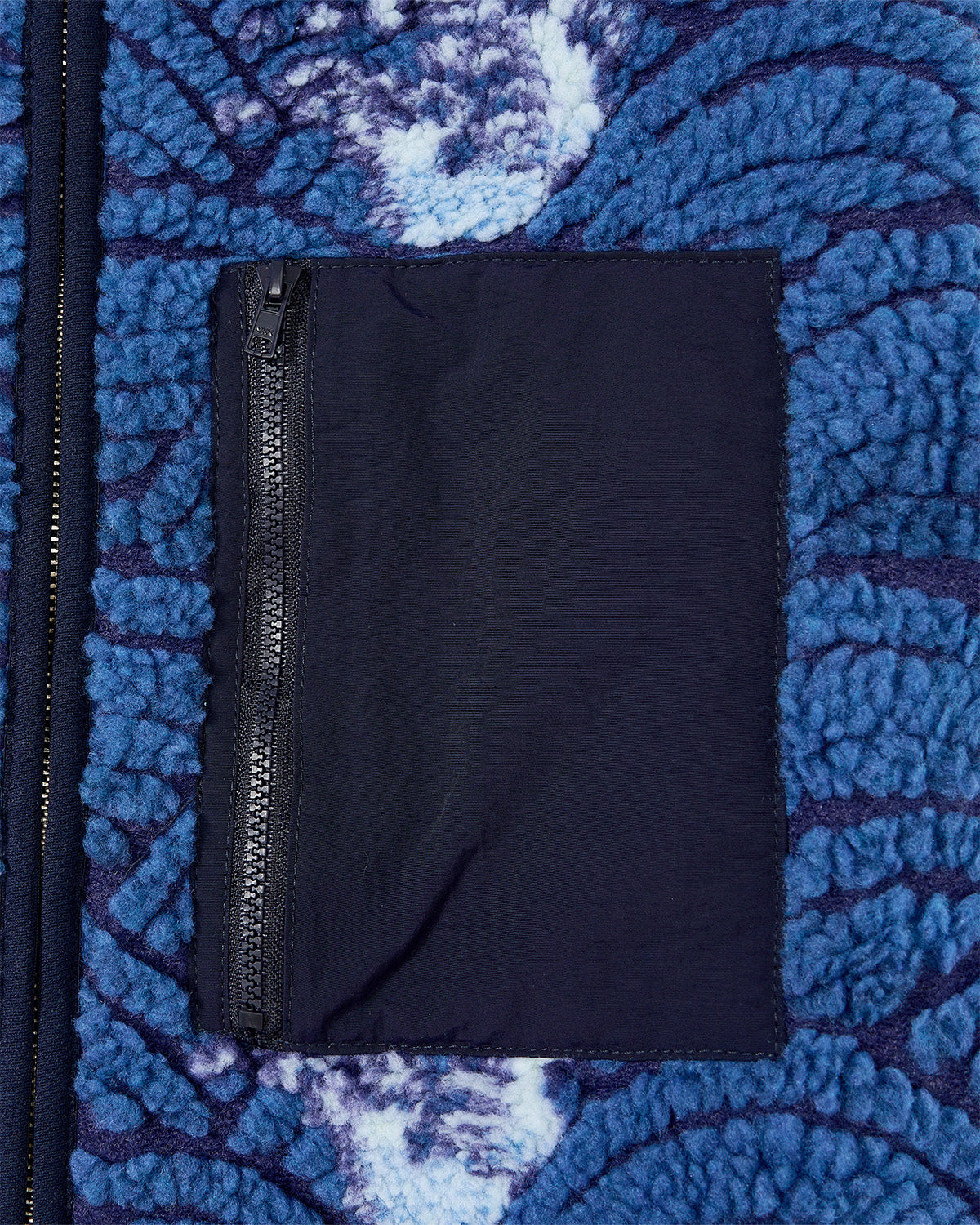 A close-up of the Sundae School BLUE WAVE FLEECE shows its blue and white embossed pile, a vertical-zip black pocket, and a custom wave jacquard inspired by Korean ocean patterns.