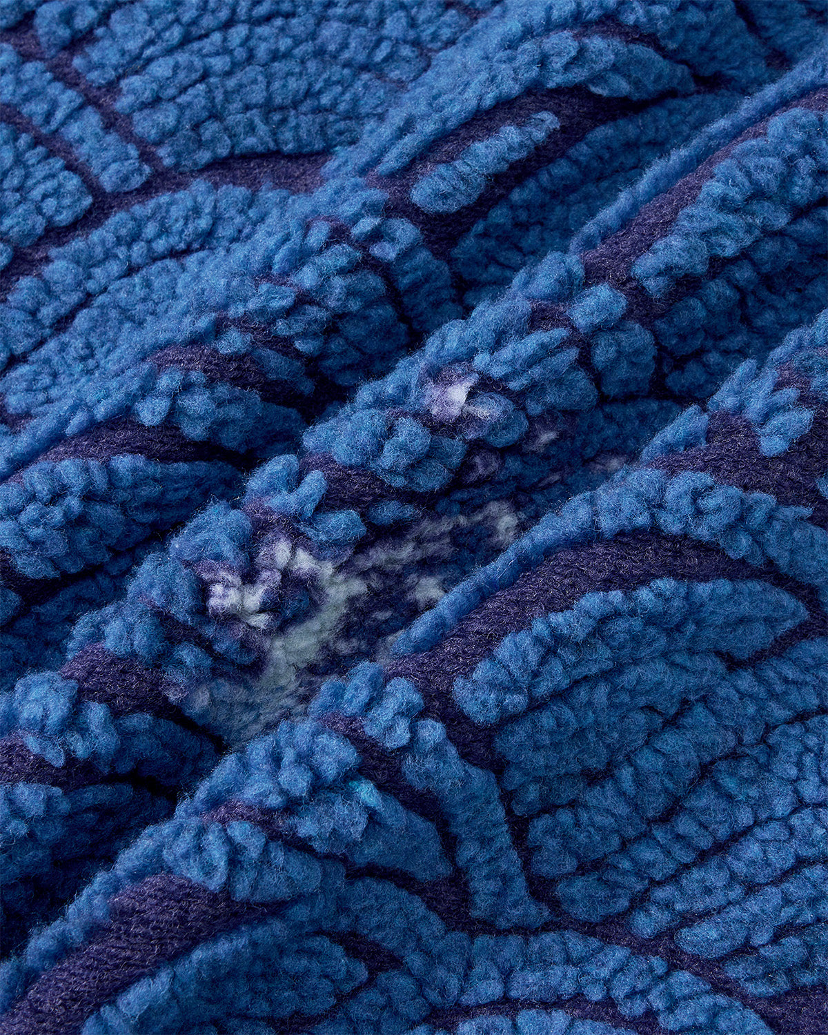 Close-up of Sundae School's BLUE WAVE FLEECE, featuring soft, thick blue fabric with raised, fluffy texture and darker wavy lines inspired by a Korean ocean pattern.