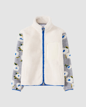 The IVORY MUGUNGHWA FLEECE by Sundae School features a white sherpa front with a high collar, grey hibiscus sleeves adorned with white and blue floral patterns, blue zipper, and two front pockets.