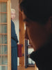 A video footage of a man staring at a woman from distance then proceeding to hide behind a door as woman looks back at him 