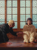 A man offering Sundae Flowers mochi gummies to a woman wearing Sundae School Pleated Duvet Puffer