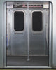 A person in Sundae School's NAVY SAILOR WINDBREAKER stands in a subway car, pairing the jacket with a matching skirt, white shirt, black tie, and a UV-protective navy baseball cap, as subway doors and a route map appear behind them.