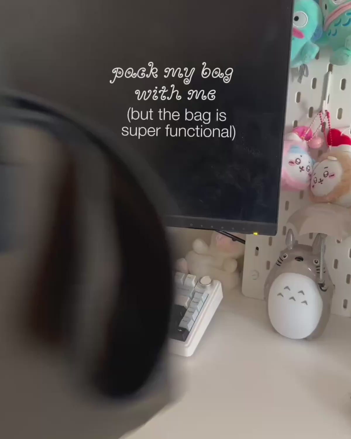 A close-up video showing how to pack an olive green Sundae School Bojagi tie tote bag. Hands load a laptop, planner, journal, sunglasses, and snacks into the bag, demonstrating features like key hooks, interior pockets, zippered compartments, and side tie straps that expand the bag's capacity.