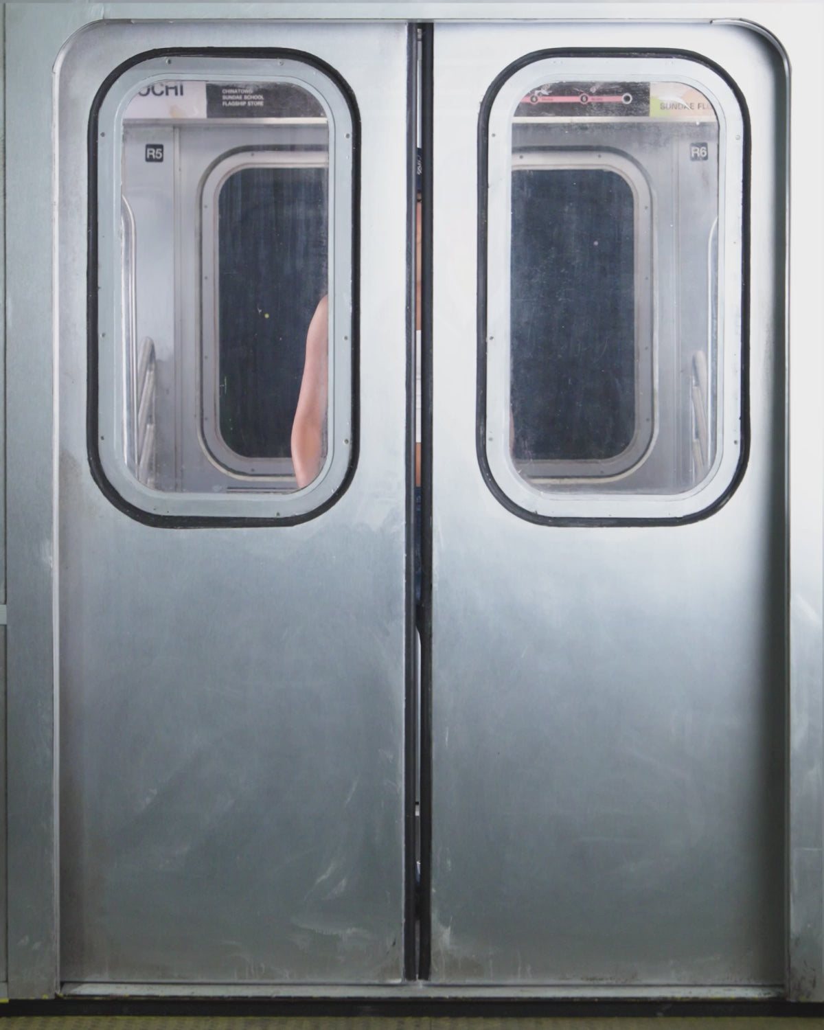 Wearing Sundae School's MEDIUM BLUE FRESHMAN FIT DENIM, a person stands by subway doors with a crowd rushing in.