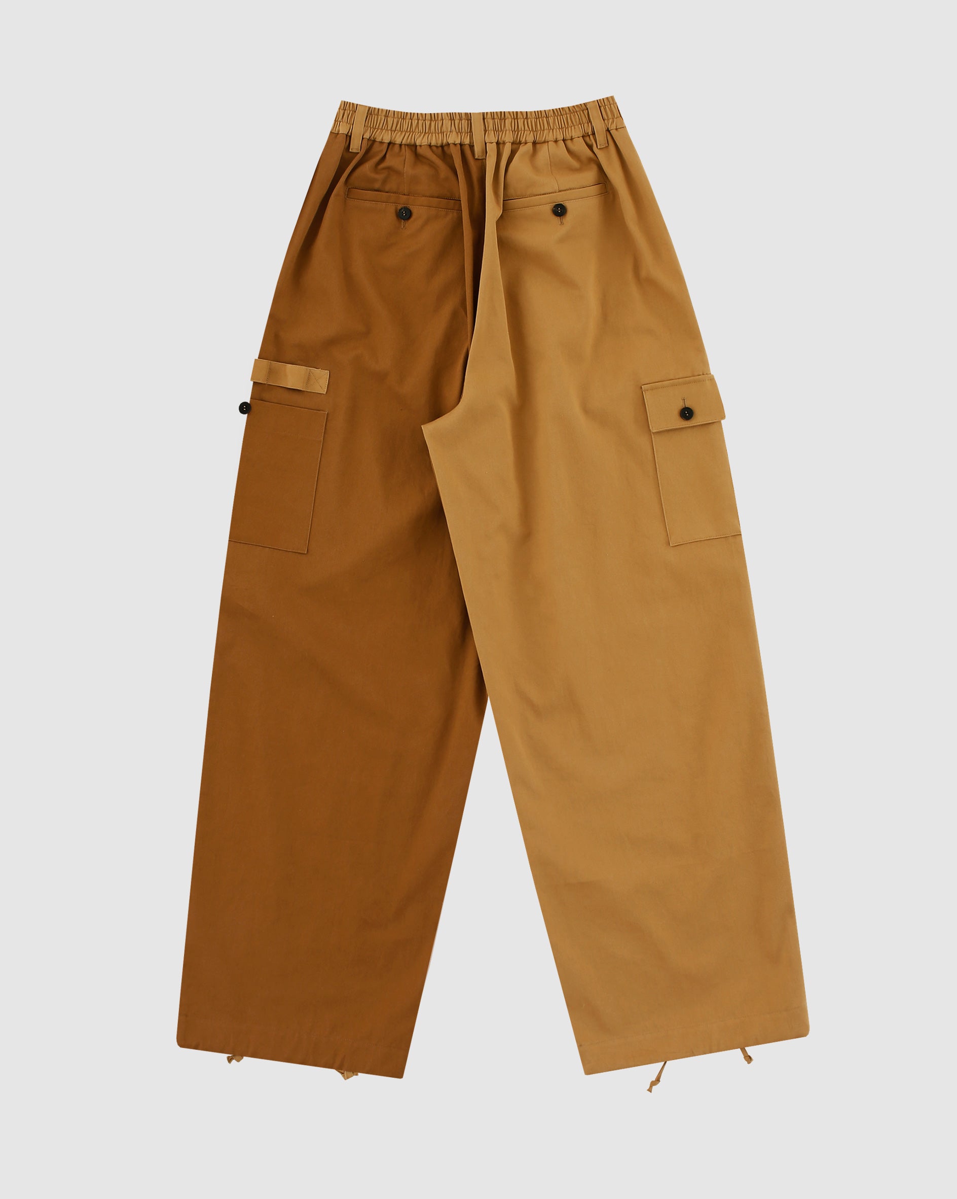 The Tan Pleated Hanbok Cargo Pants by Sundae School feature a wide-leg, two-tone Korean-inspired design with an elastic waistband, side buttoned cargo pockets, and adjustable hem drawstrings for versatile style.